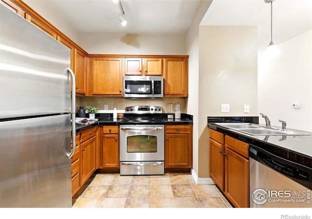 2450 Windrow Dr Unit E106, Fort Collins, CO 80525 - kitchen featuring stainless steel appliances, brown cabinetry, and pendant lighting