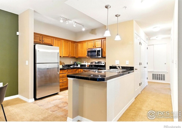 2450 Windrow Dr Unit E106, Fort Collins, CO 80525 - kitchen with appliances with stainless steel finishes, brown cabinets, a peninsula, hanging light fixtures, and light carpet