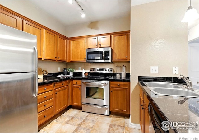2450 Windrow Dr Unit E106, Fort Collins, CO 80525 - kitchen with stainless steel appliances, brown cabinets, hanging light fixtures, and track lighting