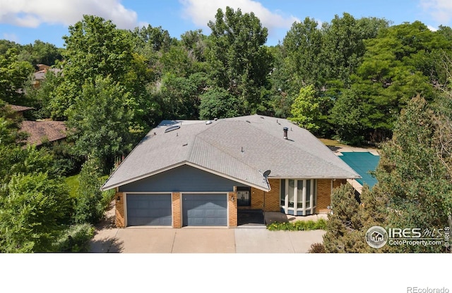 1323 Horizon Ln, Longmont, CO 80501 - view of front of house with driveway, a garage, brick siding, and a shingled roof