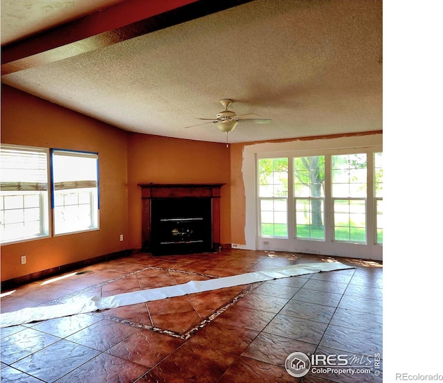 18082 County Road 25, Brush, CO 80723 - unfurnished living room featuring healthy amount of natural light, ceiling fan, vaulted ceiling, marble look tile flooring, and a textured ceiling