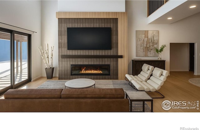 848 Trail Ridge Dr, Louisville, CO 80027 - living area featuring wood finished floors, a large fireplace, a towering ceiling, and recessed lighting