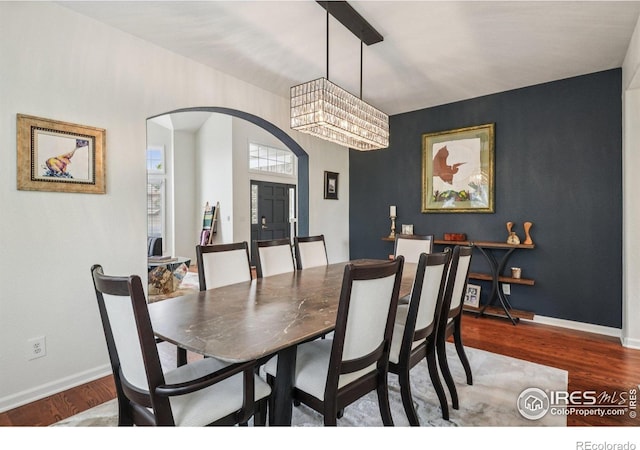 345 Onyx Way, Superior, CO 80027 - dining room featuring arched walkways, wood finished floors, and an accent wall