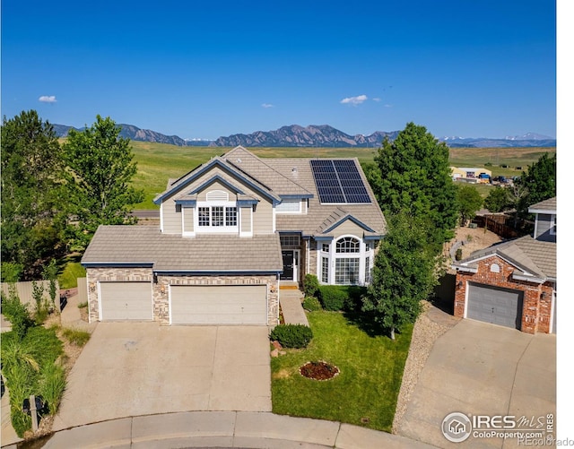 345 Onyx Way, Superior, CO 80027 - view of front of home with stone siding, driveway, a mountain view, roof mounted solar panels, and a front yard