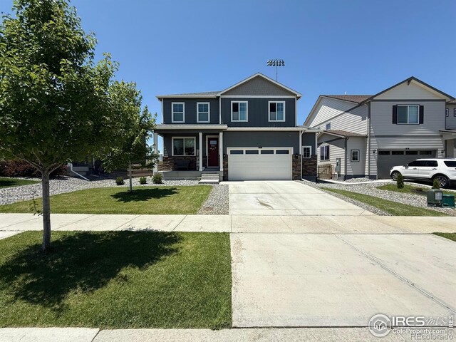 117 N 66th Ave, Greeley, CO 80634 - view of front of house with stone siding, a garage, driveway, a front yard, and a porch