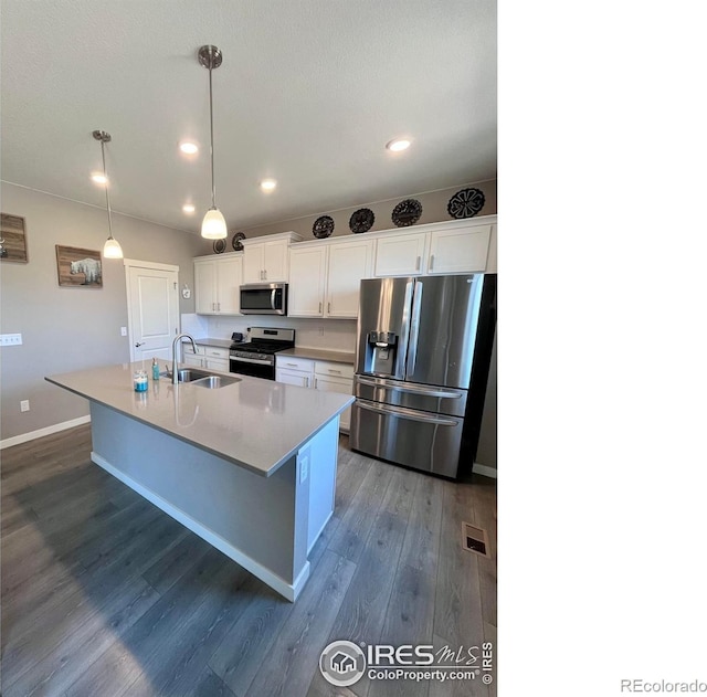 117 N 66th Ave, Greeley, CO 80634 - kitchen featuring appliances with stainless steel finishes, dark wood-style floors, white cabinets, a kitchen island with sink, and recessed lighting