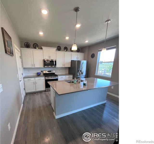 117 N 66th Ave, Greeley, CO 80634 - kitchen with stainless steel appliances, dark wood-type flooring, white cabinetry, a center island with sink, and pendant lighting