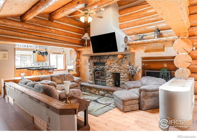 24043 Eagle Cliff Trl, Conifer, CO 80433 - living room with hardwood / wood-style floors, rustic walls, ceiling fan, beamed ceiling, and a stone fireplace