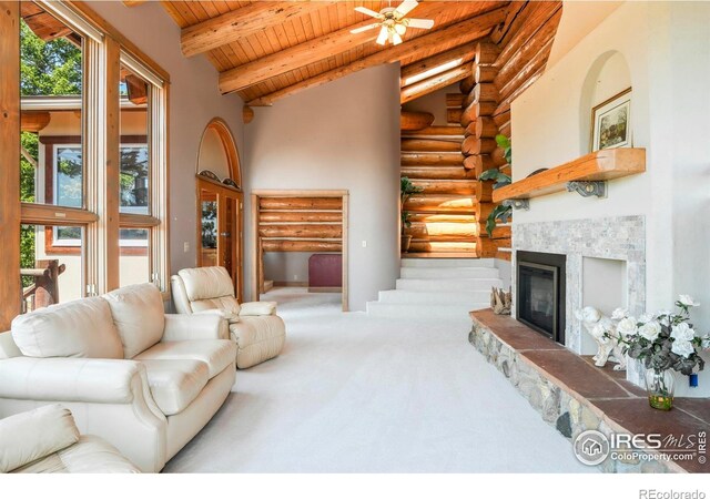 24043 Eagle Cliff Trl, Conifer, CO 80433 - living room featuring log walls, a wooden ceiling with exposed beams, a glass covered fireplace, carpet floors, and a towering ceiling