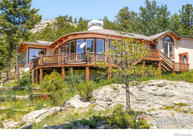 24043 Eagle Cliff Trl, Conifer, CO 80433 - view of front facade with a deck, stucco siding, stairway, and a chimney