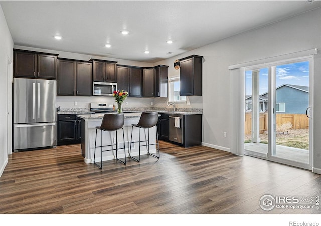 2310 Angus St, Mead, CO 80542 - kitchen featuring stainless steel appliances, dark wood finished floors, dark brown cabinetry, a kitchen bar, and a kitchen island