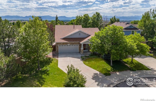 2384 Ponderosa Pl, Erie, CO 80516 - obstructed view of property featuring concrete driveway, a garage, a front yard, a mountain view, and stone siding