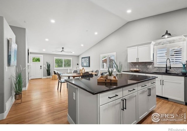 2384 Ponderosa Pl, Erie, CO 80516 - kitchen featuring dark countertops, ceiling fan, light wood finished floors, white cabinetry, and backsplash