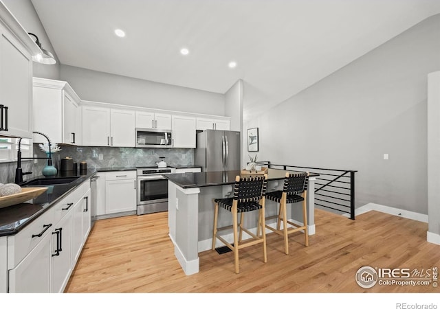 2384 Ponderosa Pl, Erie, CO 80516 - kitchen with appliances with stainless steel finishes, a kitchen island, dark countertops, white cabinetry, and recessed lighting