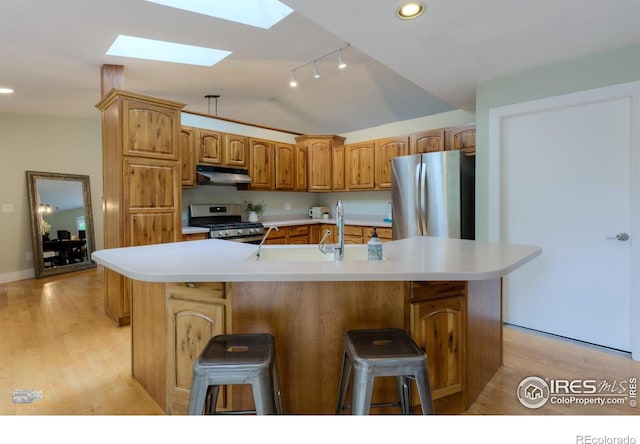 419 Centennial Dr, Louisville, CO 80027 - kitchen featuring appliances with stainless steel finishes, a skylight, under cabinet range hood, vaulted ceiling, and an island with sink