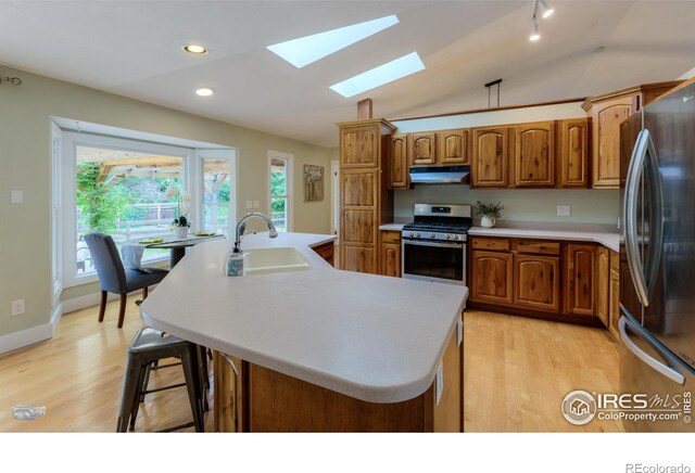 419 Centennial Dr, Louisville, CO 80027 - kitchen featuring appliances with stainless steel finishes, a skylight, light wood-style flooring, brown cabinets, and recessed lighting