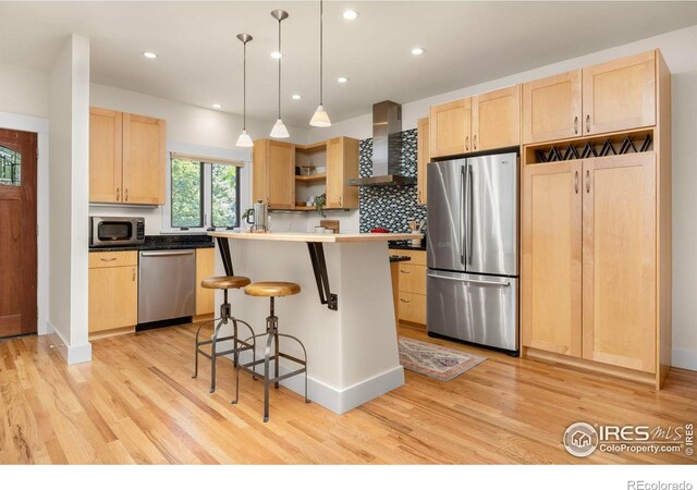 1260 Claremont Dr, Boulder, CO 80305 - kitchen with stainless steel appliances, wall chimney exhaust hood, light brown cabinets, a kitchen bar, and recessed lighting