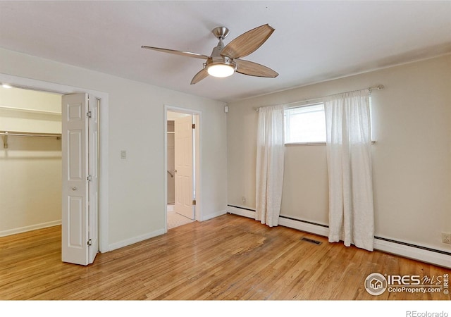 353 S Niagara St, Denver, CO 80224 - unfurnished bedroom with light wood-style flooring, baseboard heating, and a walk in closet