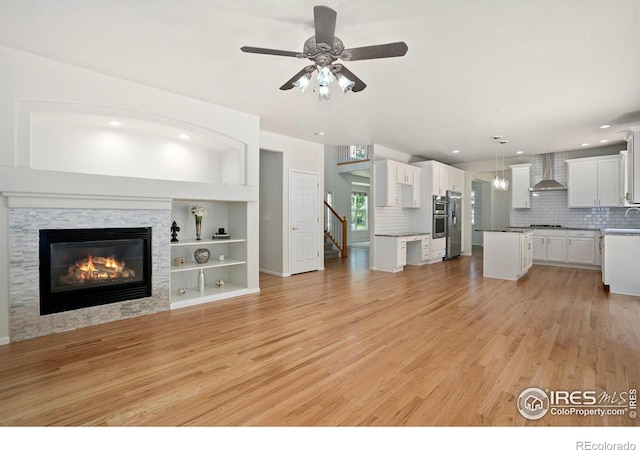 10216 Sandy Ridge Ct, Firestone, CO 80504 - unfurnished living room with light wood-style floors, a stone fireplace, a ceiling fan, stairs, and recessed lighting