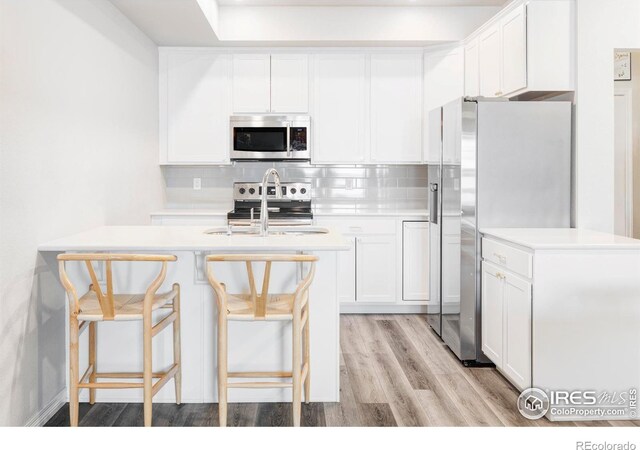 897 Winding Brook Dr, Berthoud, CO 80513 - kitchen with appliances with stainless steel finishes, light countertops, tasteful backsplash, light wood-style floors, and white cabinets