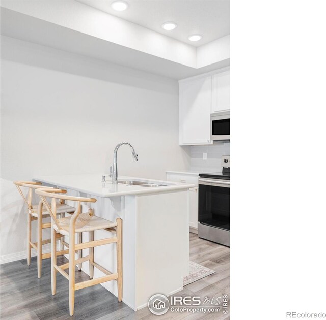 897 Winding Brook Dr, Berthoud, CO 80513 - kitchen with electric stove, white microwave, light wood-type flooring, a kitchen bar, and recessed lighting