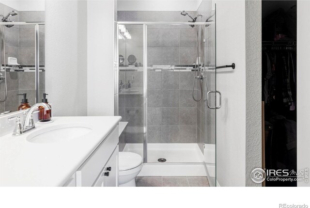 897 Winding Brook Dr, Berthoud, CO 80513 - bathroom with vanity, a stall shower, a spacious closet, and tile patterned flooring