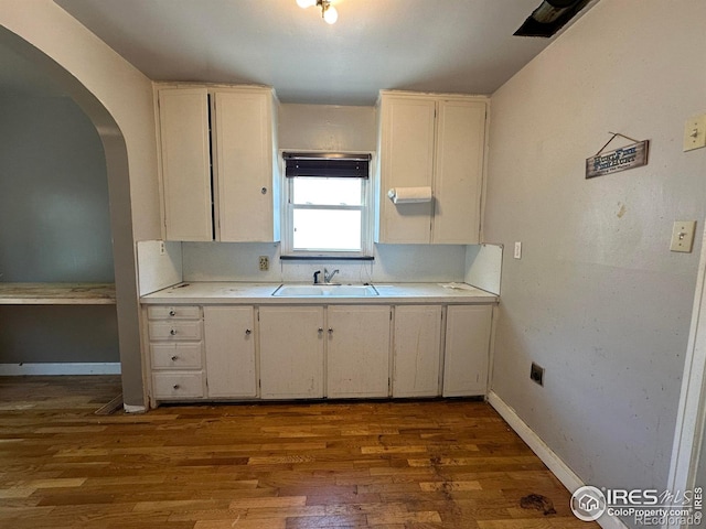 305 Euclid St, Fort Morgan, CO 80701 - kitchen with light countertops, wood finished floors, arched walkways, and white cabinets