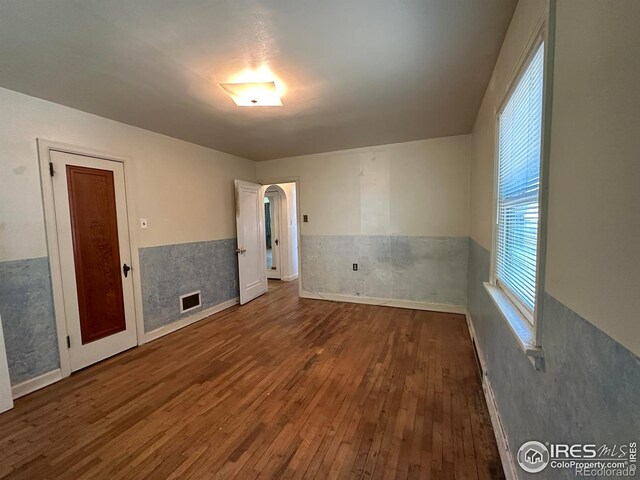 305 Euclid St, Fort Morgan, CO 80701 - unfurnished room featuring hardwood / wood-style floors, a wainscoted wall, and arched walkways