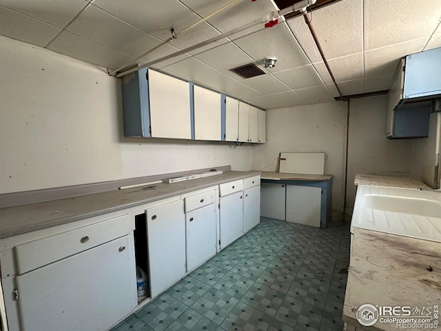 305 Euclid St, Fort Morgan, CO 80701 - kitchen featuring a paneled ceiling, light floors, light countertops, and white cabinetry