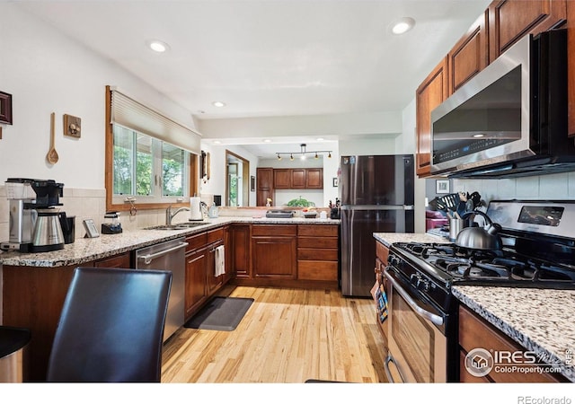 7290 Mount Sherman Rd, Longmont, CO 80503 - kitchen with appliances with stainless steel finishes, light wood-type flooring, decorative backsplash, light stone counters, and recessed lighting