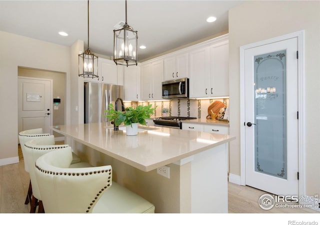 2599 Trio Falls Dr, Loveland, CO 80538 - kitchen with appliances with stainless steel finishes, light wood-style floors, white cabinetry, a breakfast bar, and recessed lighting