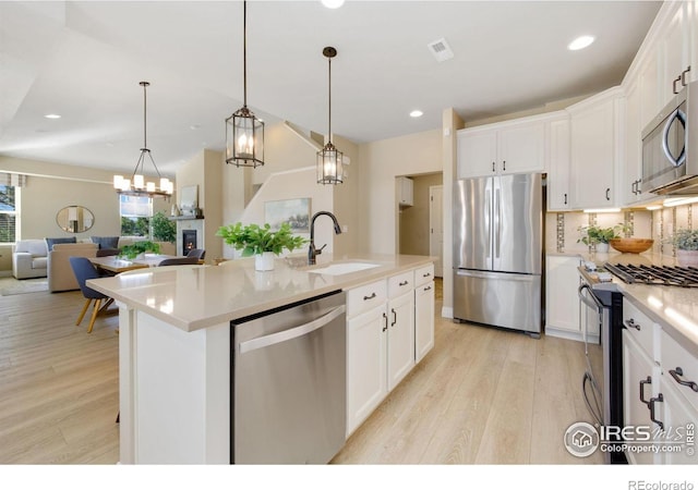 2599 Trio Falls Dr, Loveland, CO 80538 - kitchen featuring stainless steel appliances, light wood-style flooring, open floor plan, white cabinetry, and recessed lighting
