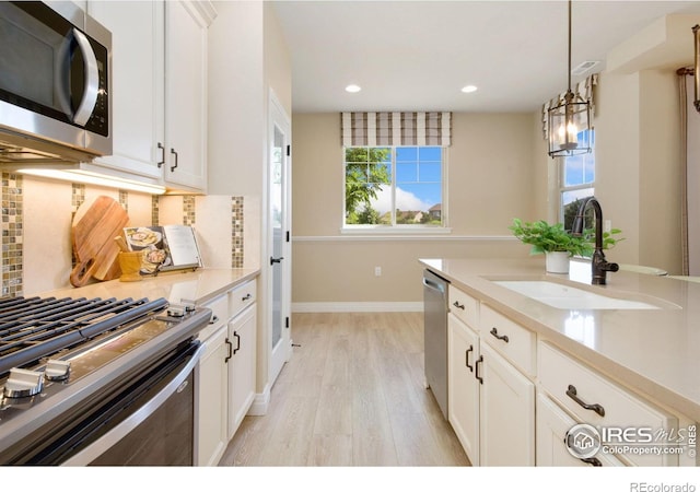 2599 Trio Falls Dr, Loveland, CO 80538 - kitchen featuring appliances with stainless steel finishes, backsplash, light wood finished floors, recessed lighting, and decorative light fixtures
