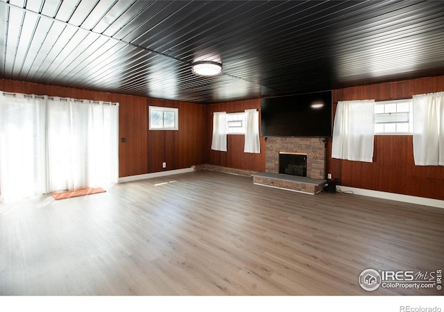 947 Holden Ln, Sterling, CO 80751 - unfurnished living room featuring a stone fireplace, wood finished floors, and wood walls