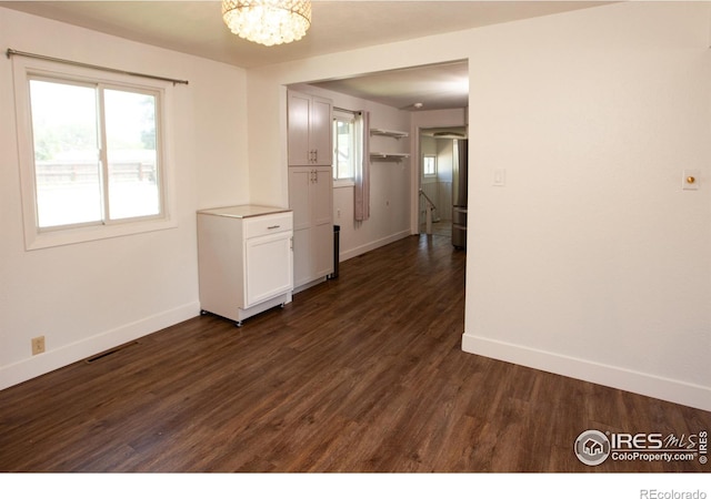 947 Holden Ln, Sterling, CO 80751 - empty room featuring dark wood-style flooring, a chandelier, and plenty of natural light