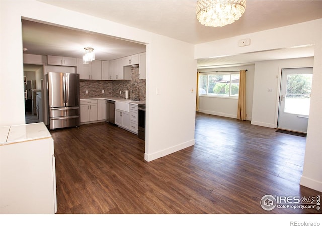 947 Holden Ln, Sterling, CO 80751 - kitchen with appliances with stainless steel finishes, decorative backsplash, a chandelier, and dark wood-style floors