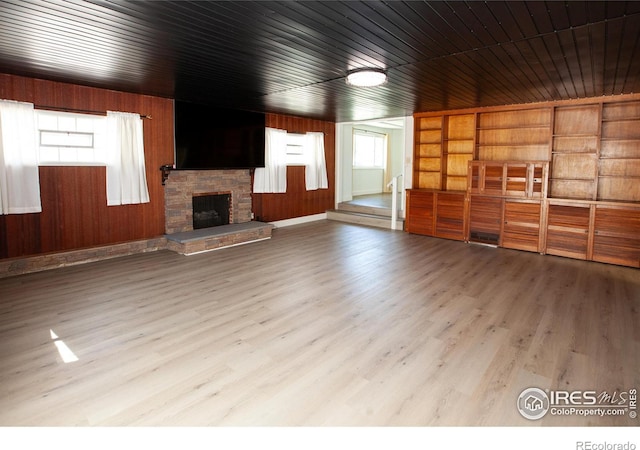 947 Holden Ln, Sterling, CO 80751 - unfurnished living room with wooden walls, wood finished floors, and a stone fireplace