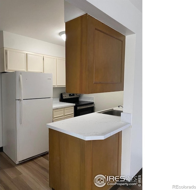 2227 Canyon Blvd Unit 359B, Boulder, CO 80302 - kitchen featuring freestanding refrigerator, stainless steel range with electric stovetop, wood finished floors, light countertops, and a peninsula