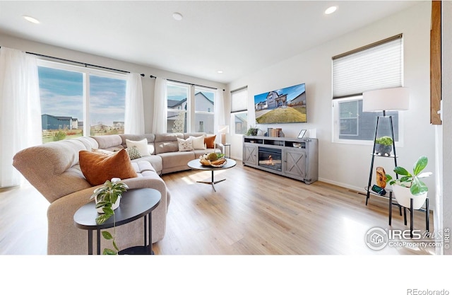 6013 Goodnight Ave, Timnath, CO 80547 - living area featuring wood finished floors, plenty of natural light, recessed lighting, and a glass covered fireplace