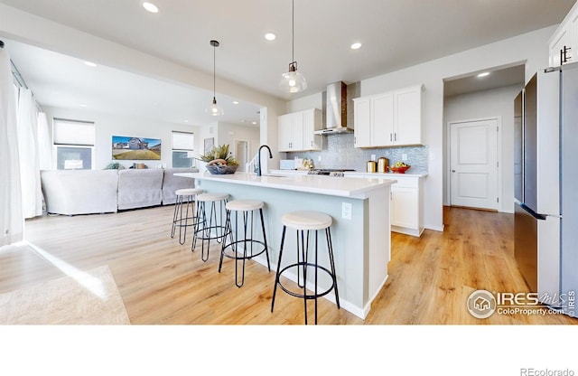 6013 Goodnight Ave, Timnath, CO 80547 - kitchen with freestanding refrigerator, wall chimney range hood, a kitchen breakfast bar, white cabinetry, and recessed lighting
