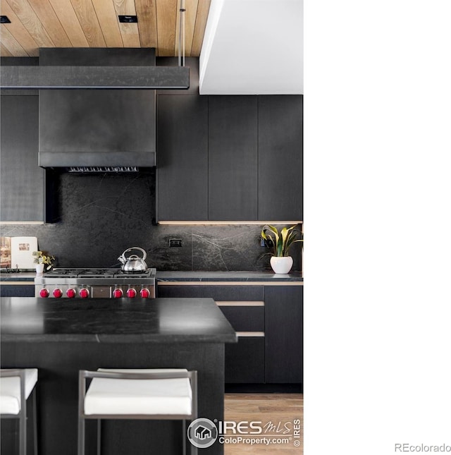 358 Arapahoe Ave Unit B, Boulder, CO 80302 - kitchen with dark countertops, a breakfast bar, backsplash, light wood-style flooring, and wood ceiling
