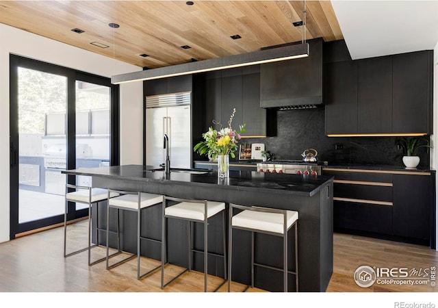358 Arapahoe Ave Unit B, Boulder, CO 80302 - kitchen featuring dark cabinets, dark countertops, built in refrigerator, decorative backsplash, and a kitchen breakfast bar