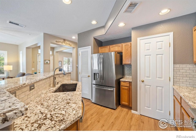 64 Whitehaven Cir, Highlands Ranch, CO 80129 - kitchen featuring stainless steel fridge, backsplash, light wood-type flooring, light stone countertops, and recessed lighting