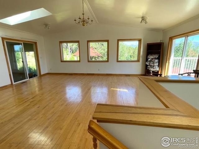 8 Valley View Dr, Nederland, CO 80466 - unfurnished living room with a skylight, wood finished floors, vaulted ceiling, crown molding, and a chandelier