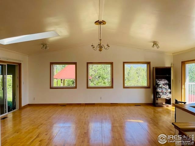 8 Valley View Dr, Nederland, CO 80466 - unfurnished living room featuring light wood-type flooring, crown molding, lofted ceiling, a chandelier, and a skylight