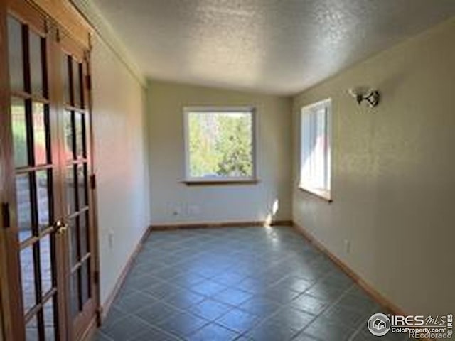 8 Valley View Dr, Nederland, CO 80466 - empty room with french doors, a textured ceiling, and dark tile patterned flooring
