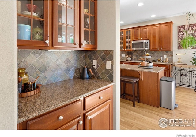 121 Osprey Ln, Lyons, CO 80540 - kitchen featuring stainless steel microwave, tasteful backsplash, brown cabinetry, light wood-type flooring, and recessed lighting