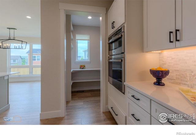 2397 Bristol St, Superior, CO 80027 - kitchen with double oven, light wood-style flooring, backsplash, white cabinets, and light countertops