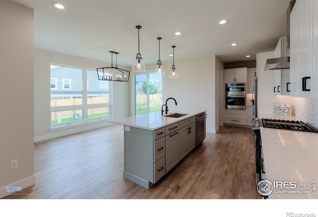 2397 Bristol St, Superior, CO 80027 - kitchen featuring appliances with stainless steel finishes, light wood finished floors, recessed lighting, a kitchen island with sink, and light countertops