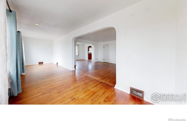 595 E Kiser Ave, Keenesburg, CO 80643 - spare room featuring arched walkways and wood finished floors